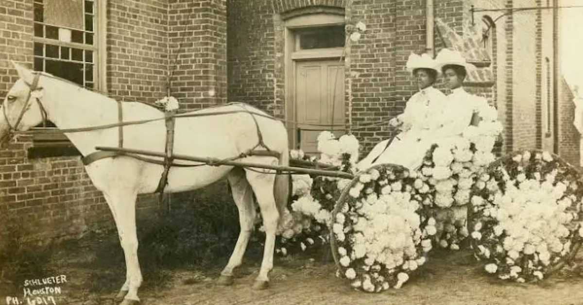Two people in a horse carriage with wheels decorated with flowers, sepia-toned