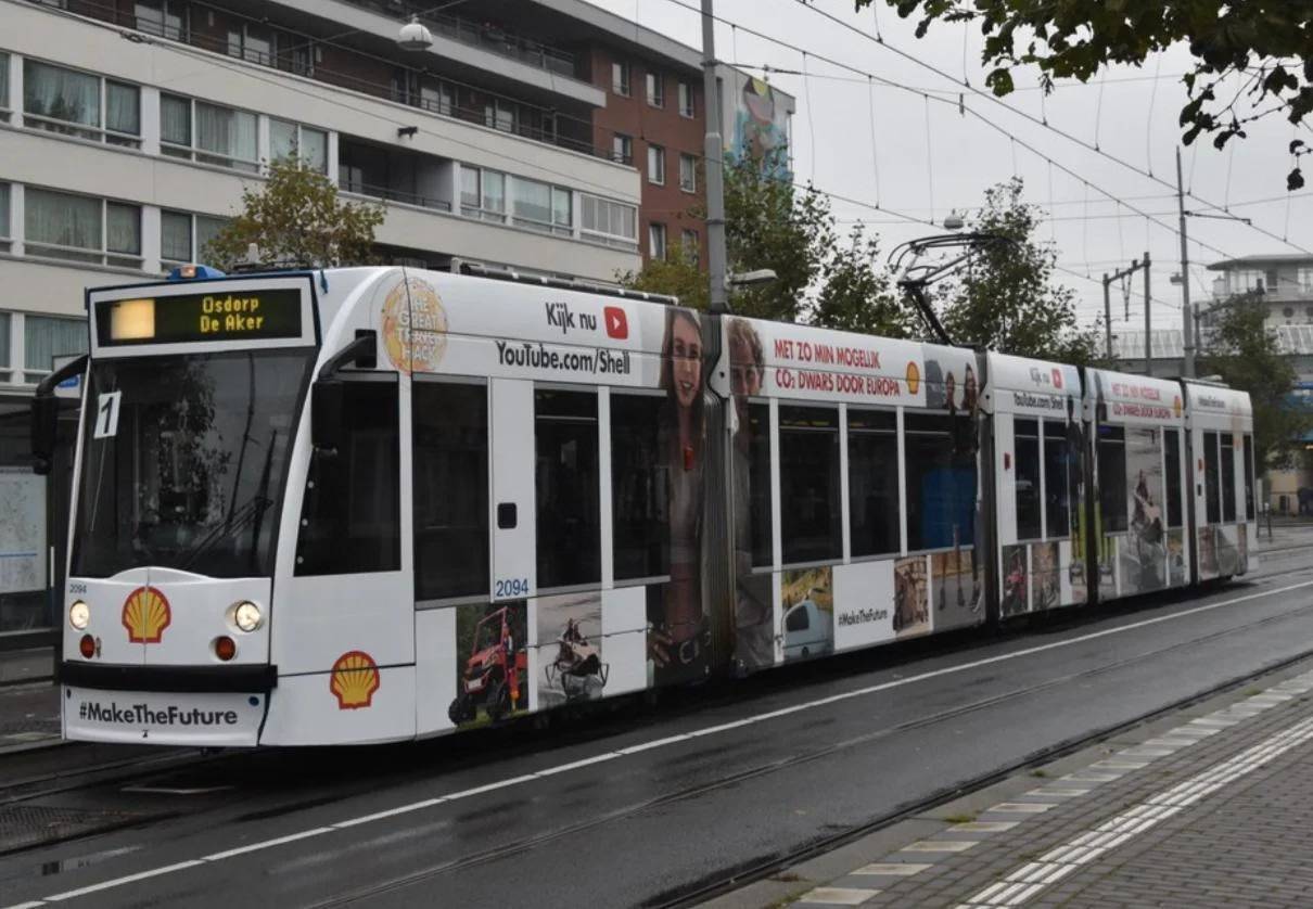A street car train with a Shell advertisement wrapped on the exterior
