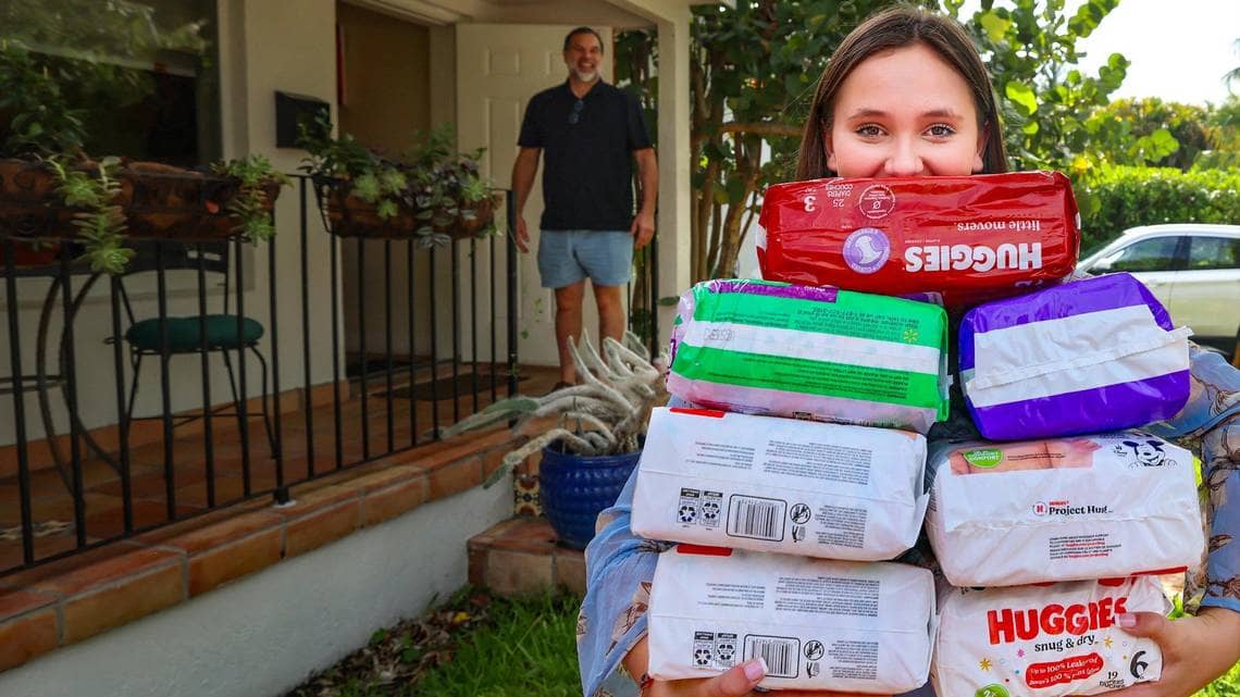 A person with arms full of diaper packs