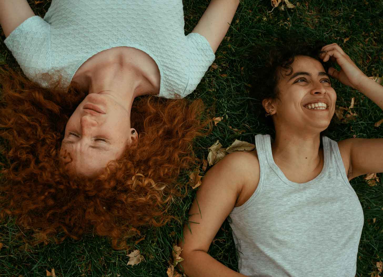 Two people laying down in the grass, pictured from overhead
