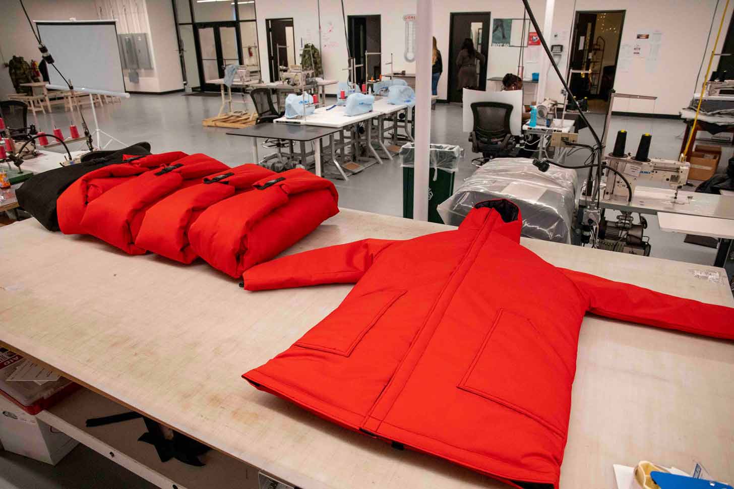 Red coats laid on a table in a larger sewing room