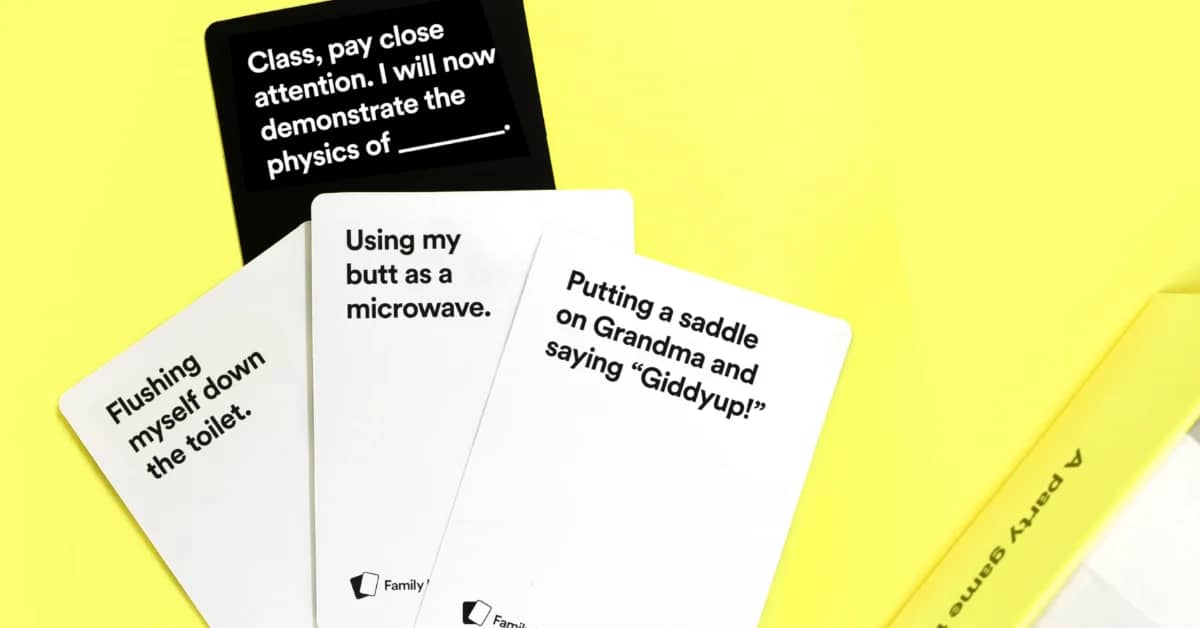 Cards laid on yellow background displaying text prompts: "Class, pay close attention. I will now demonstrate the physics of ____" on black card at top; "Flushing myself down the toilet," "Using my butt as a microwave," and "Putting a saddle on Grandma and saying 'Giddyup!'" on white cards below.