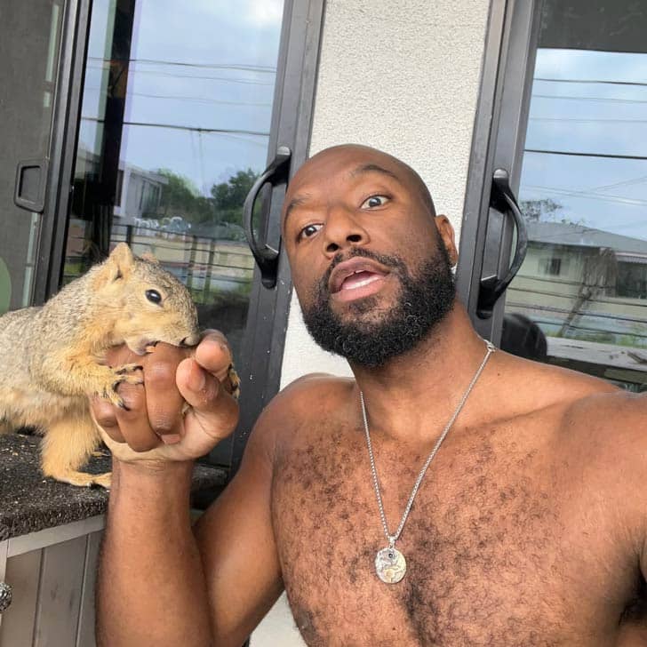A man taking a selfie with a squirrel holding and biting his finger