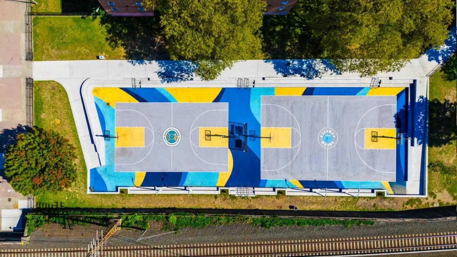 Bird's-eye view of two colorfully painted basketball courts in a park 