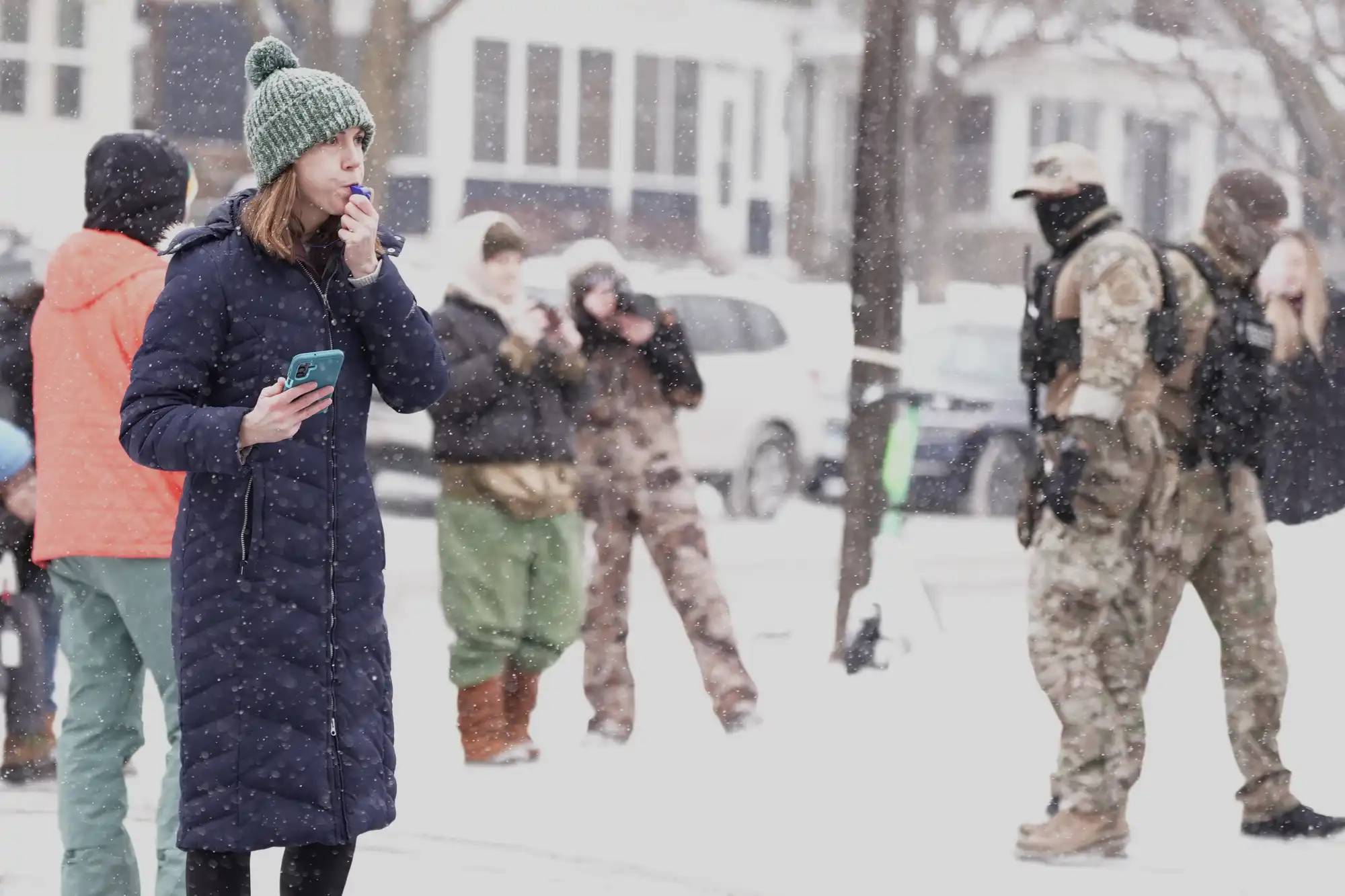 Person in a long black coat holding a phone and blowing a whistle