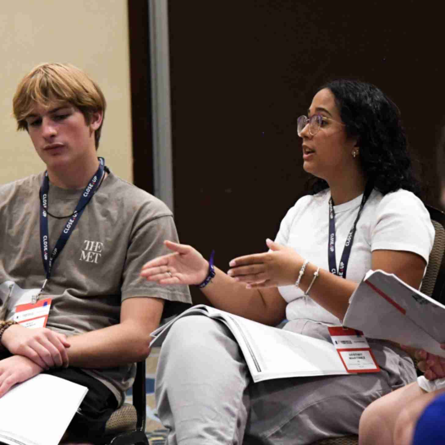 Two people sitting in chairs, one is talking