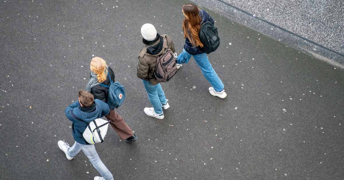 Four students with backpacks, pictured from above