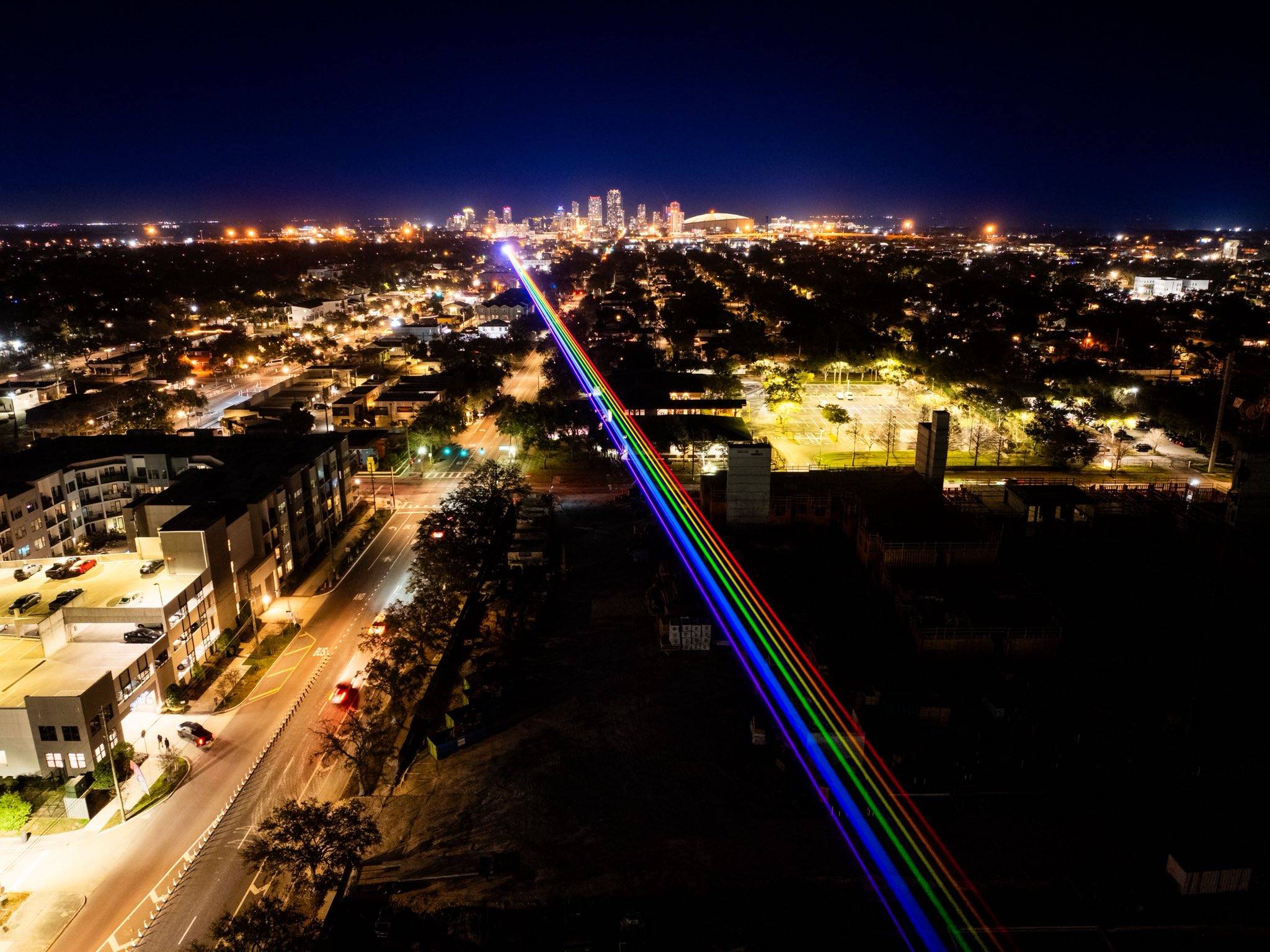Lasers making a rainbow line over a city at night