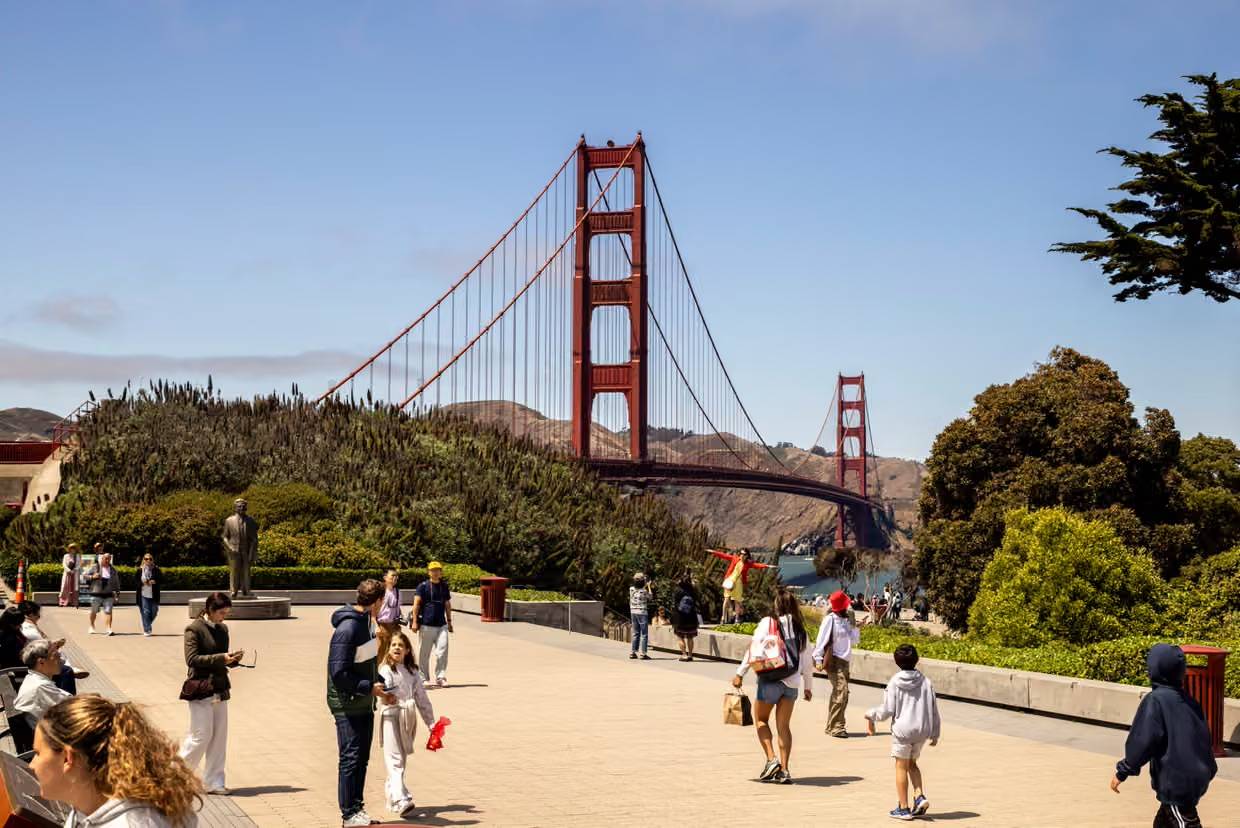 People walking in a park with the Golden Gate Bridge in the background
