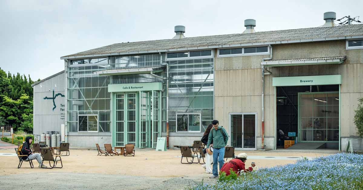 Exterior of an industrial style building with people nearby and signs that say "cafe and restaurant" and "brewery"
