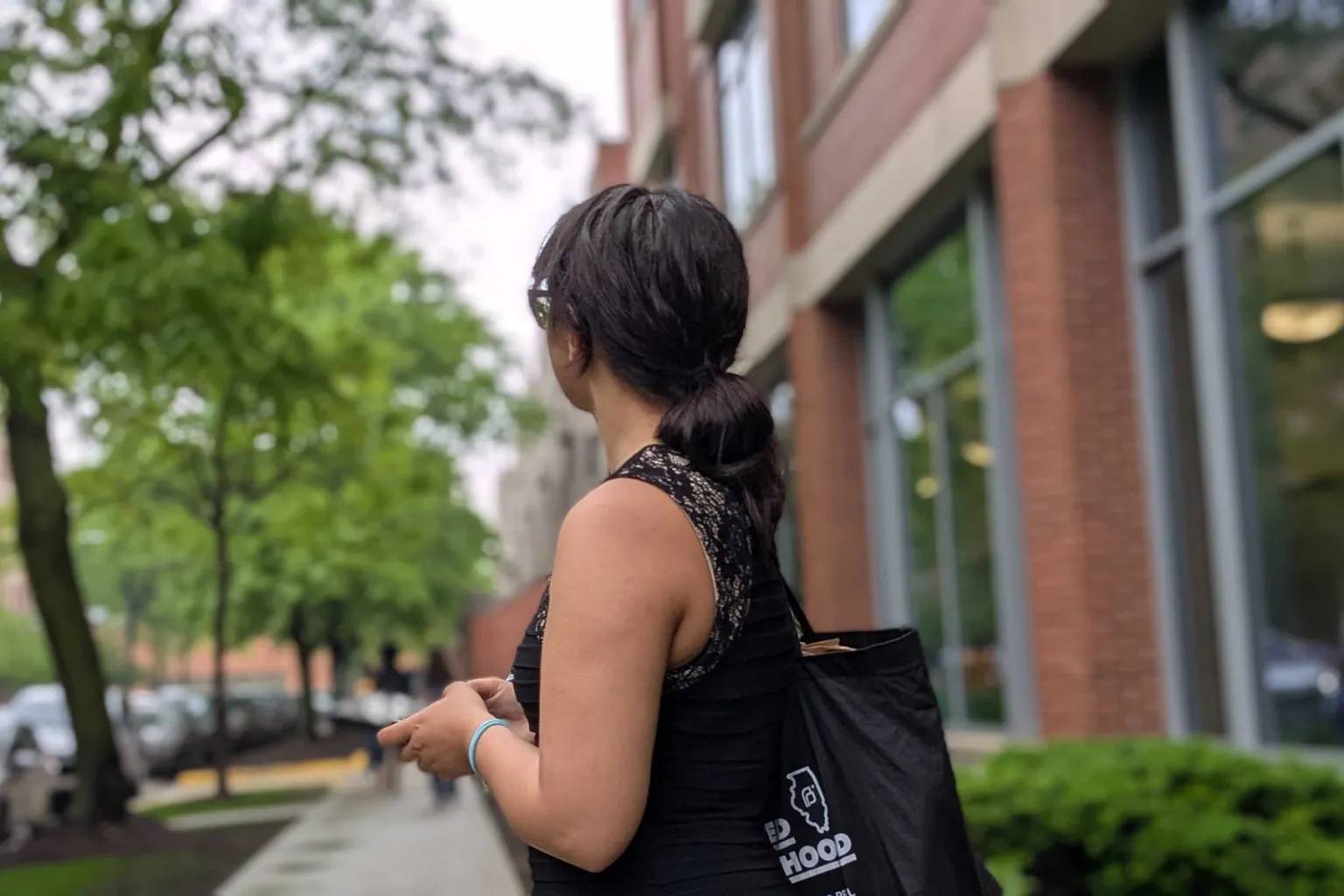 A person standing with a black tote bag on a sidewalk