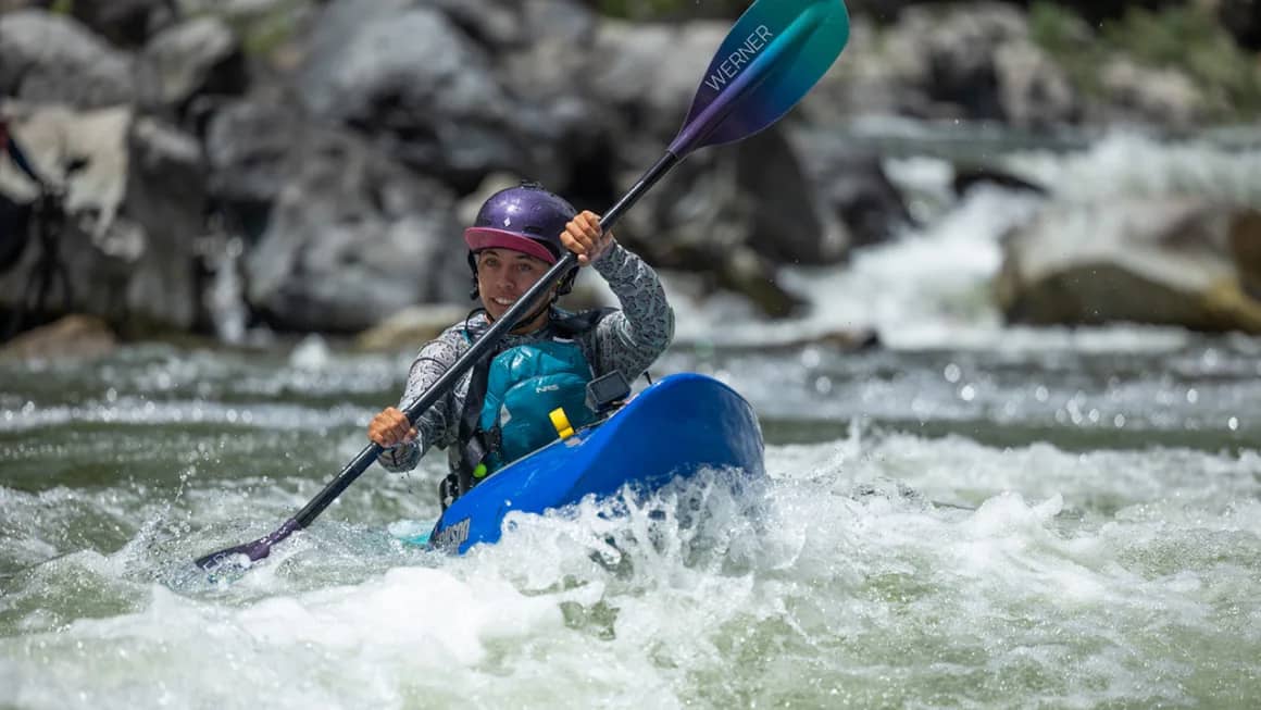Person in a kayak and helmet paddling in whitewater