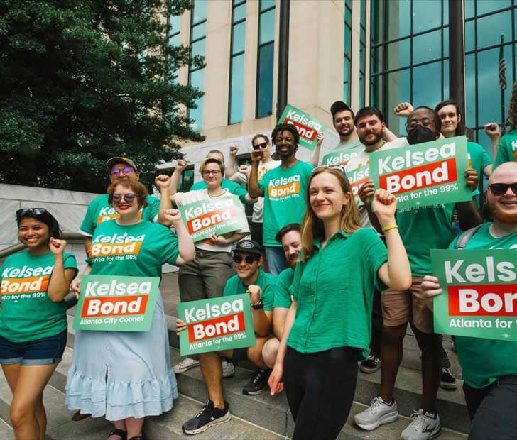 Kelsea Bond in a green shirt surrounded by supporters holding Kelsea Bond signs
