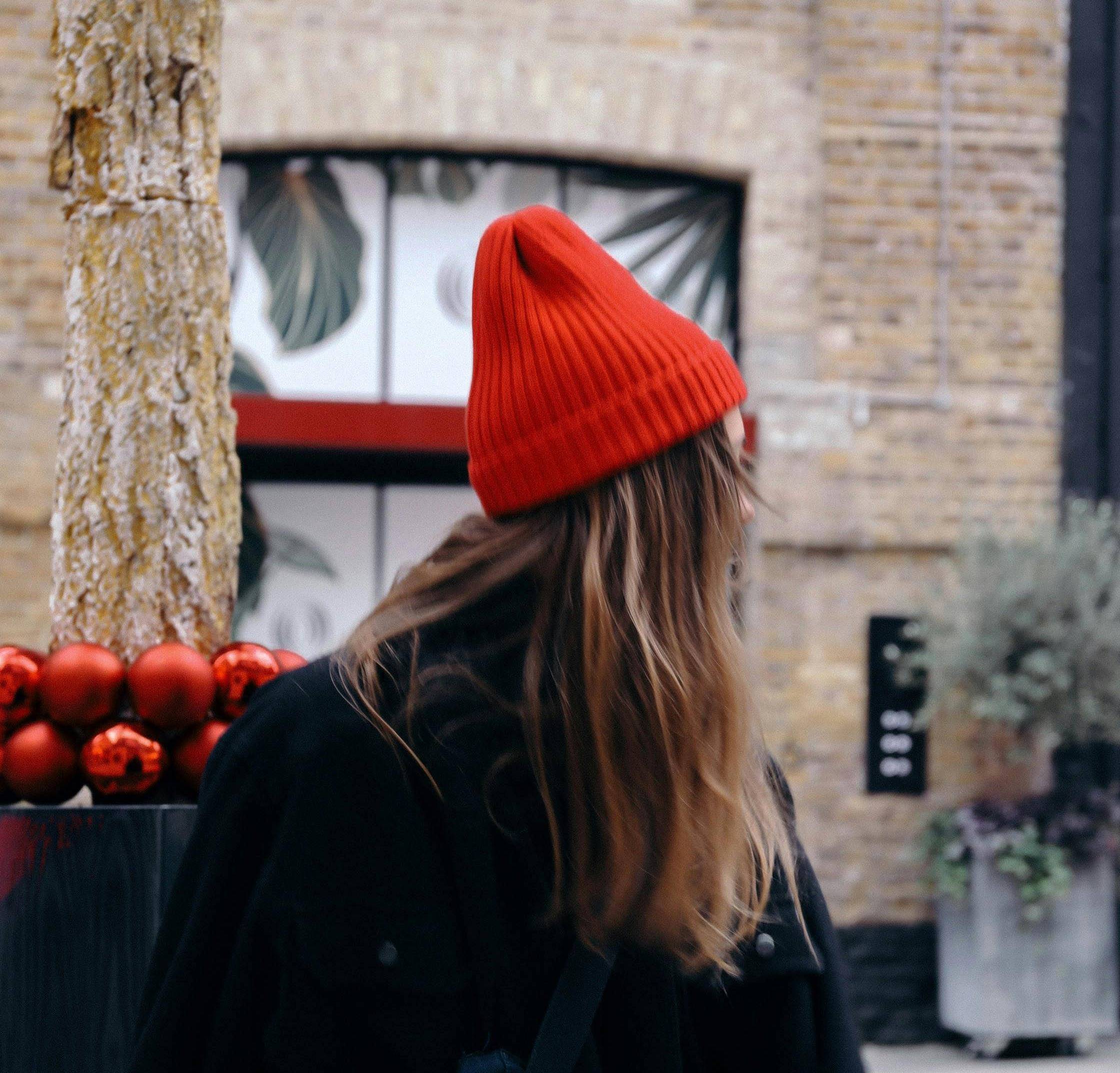 Person looking away wearing a black coat and red beanie