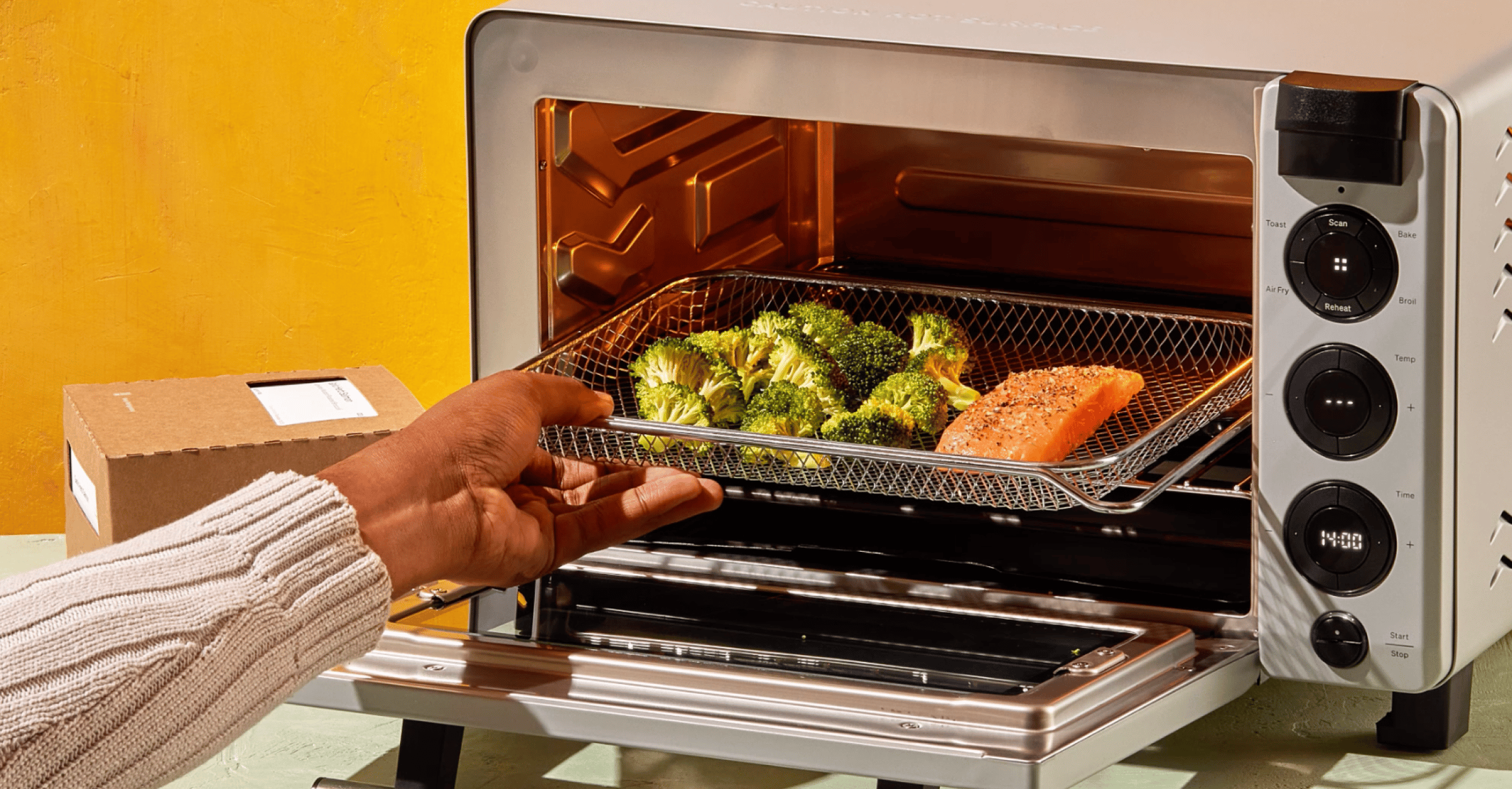 A countertop oven with a tray of broccoli and salmon in it