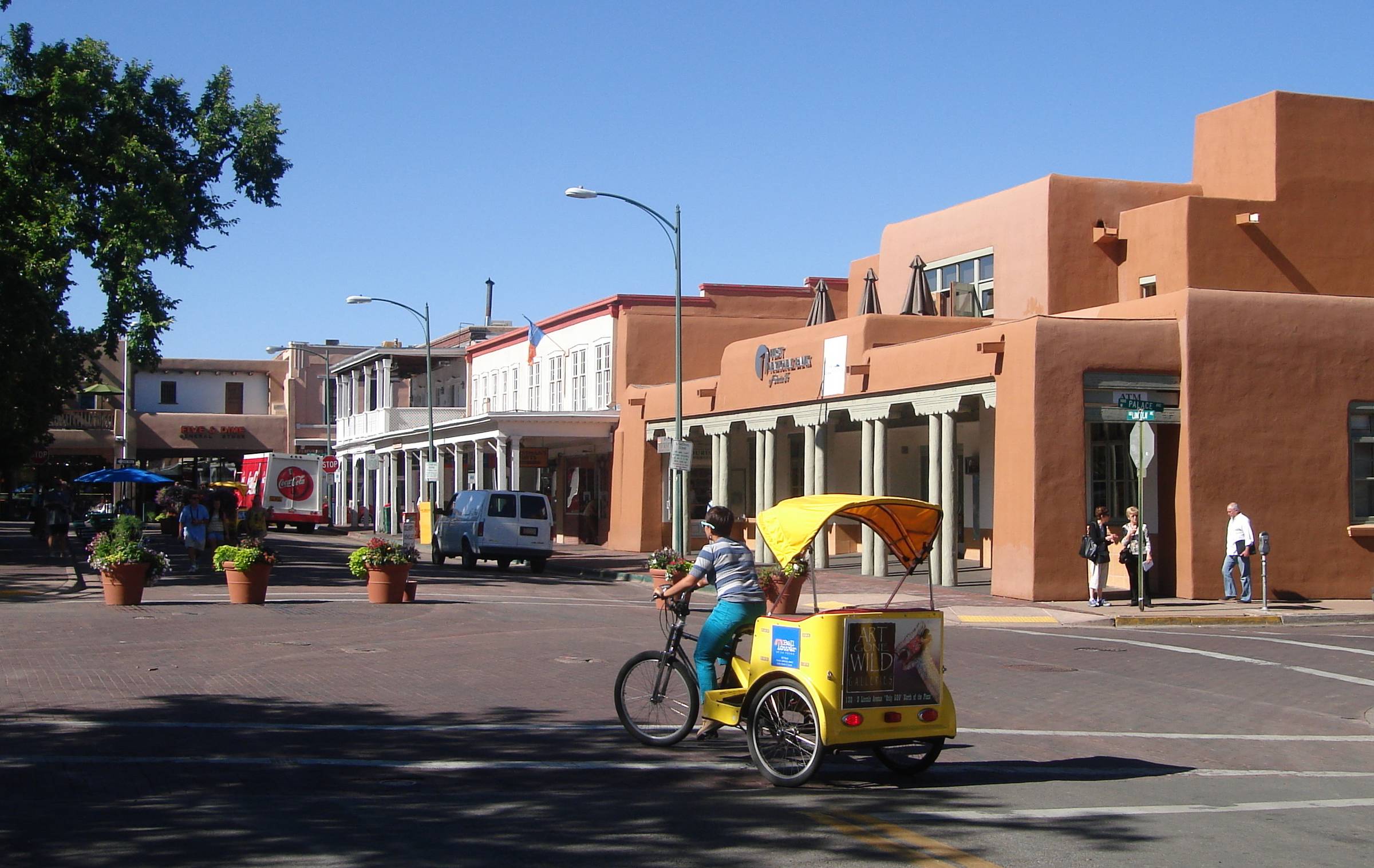 A person pedaling a pedicab through downtown Santa Fe