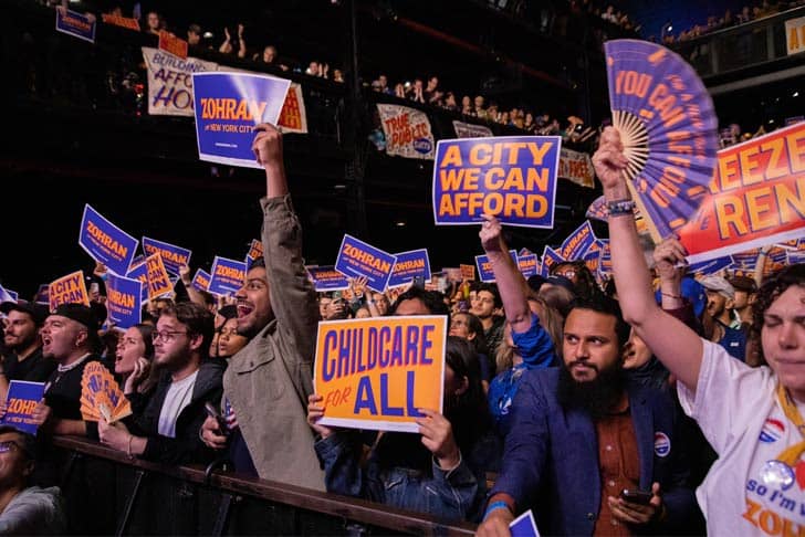 People holding signs at a Zohran Mamdani rally
