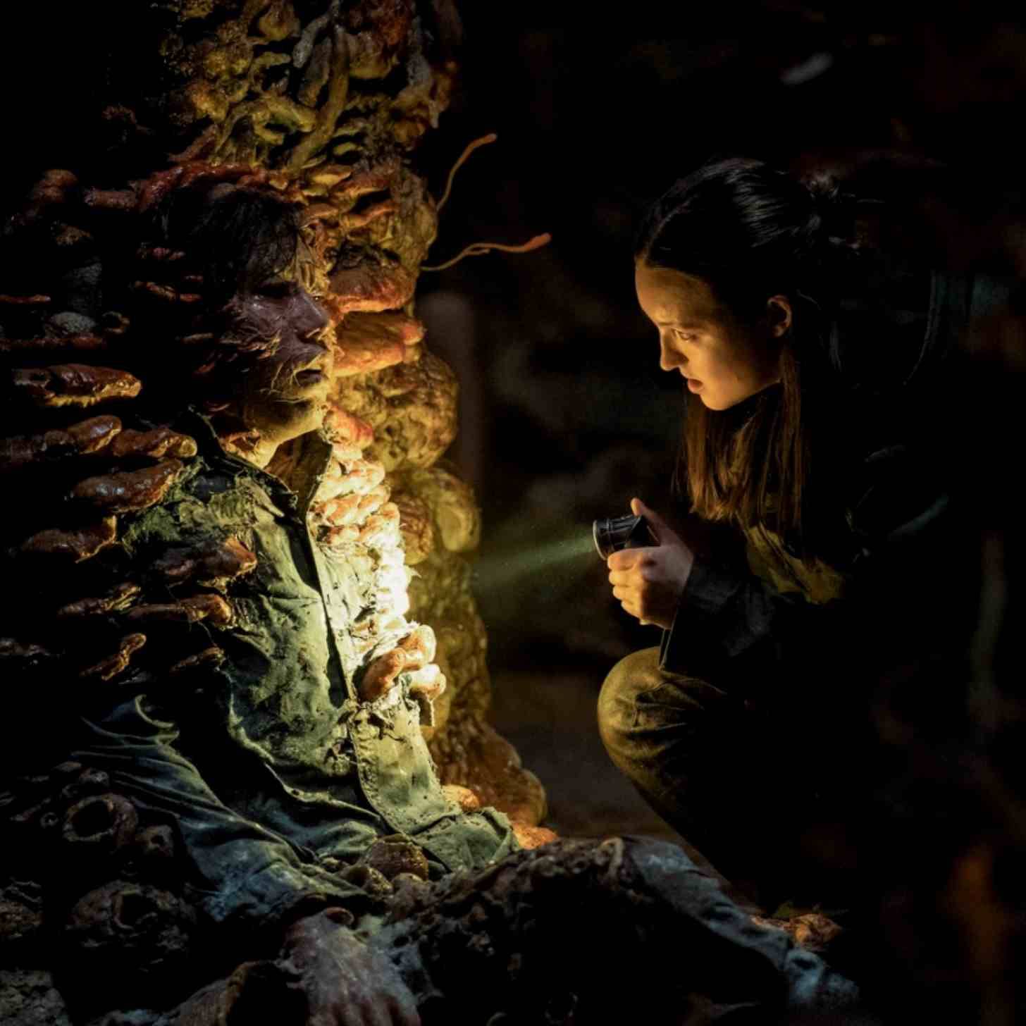 The Last of Us actor holding a flashlight on a person being consumed by fungi