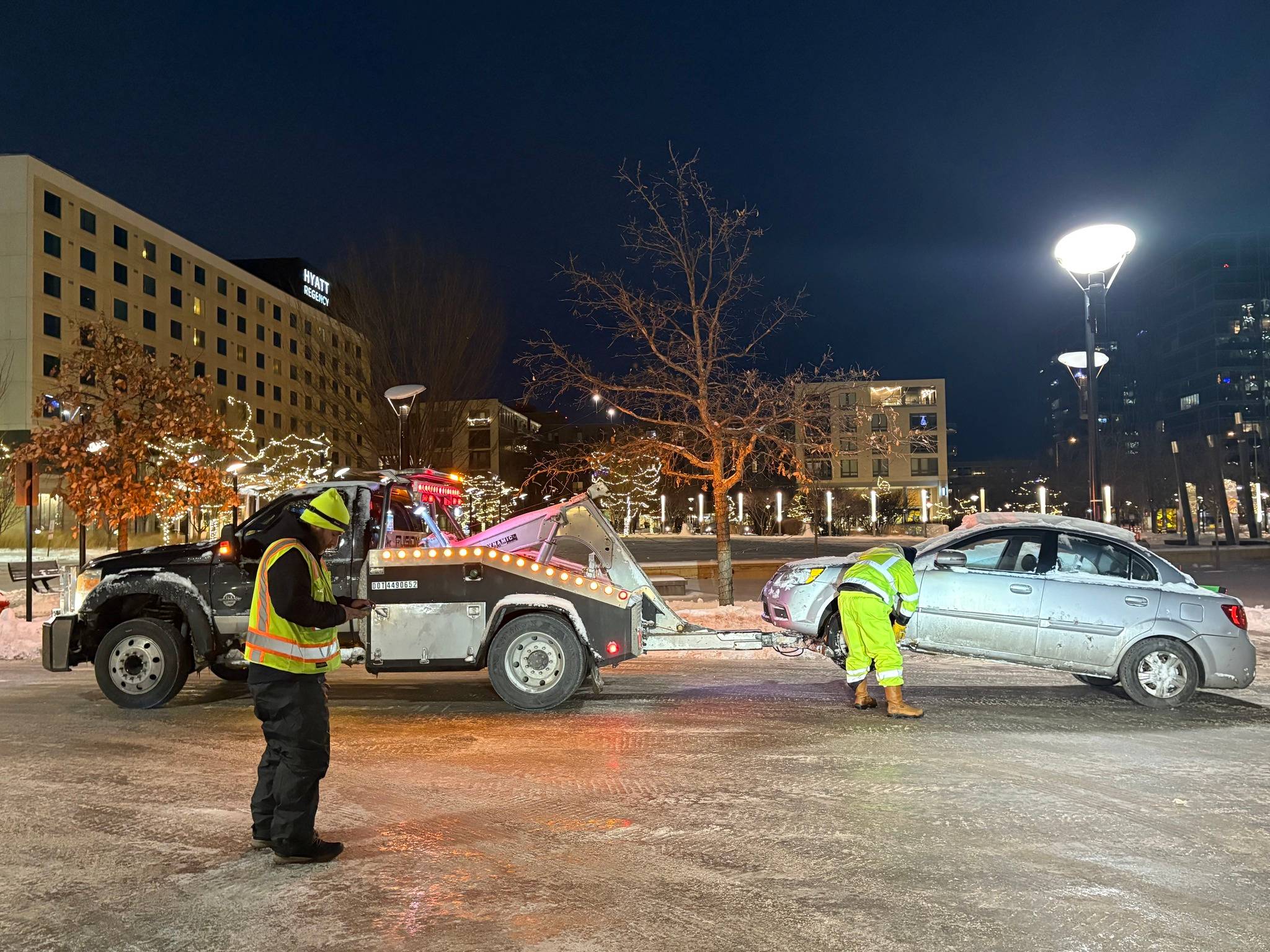 Two people operating a tow truck at night