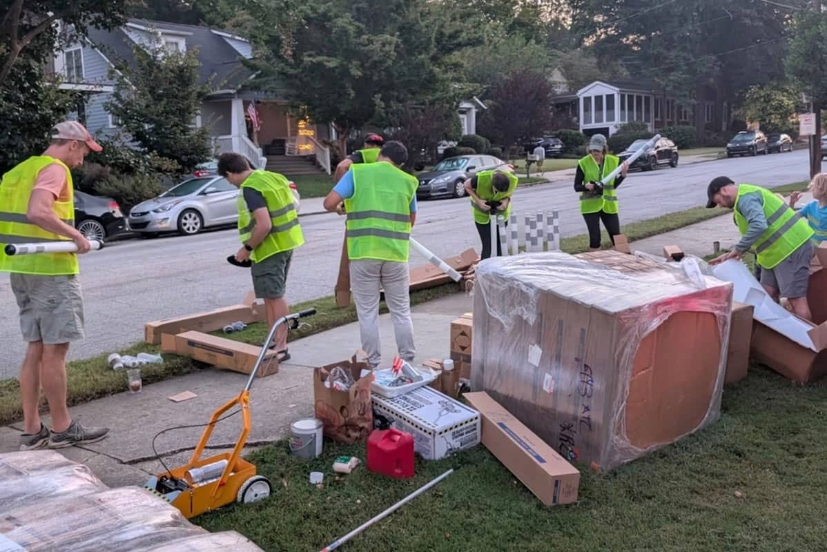Seven people in yellow neon vests preparing supplies to set up a bike lane