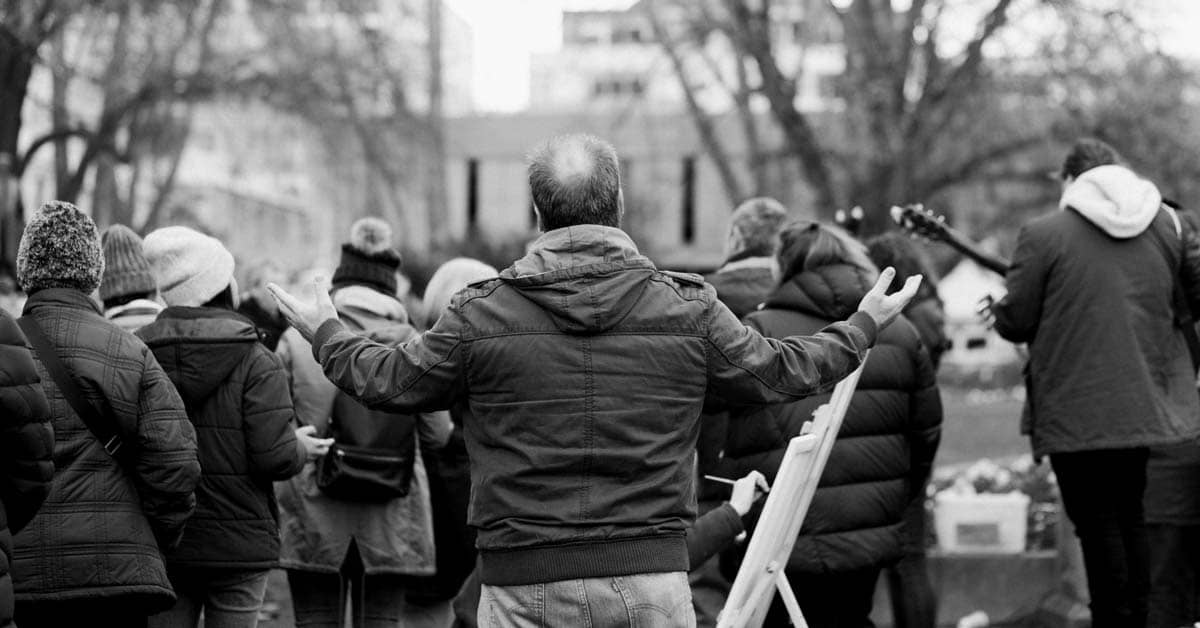 Group of people pictured from behind holding instruments and their hands up