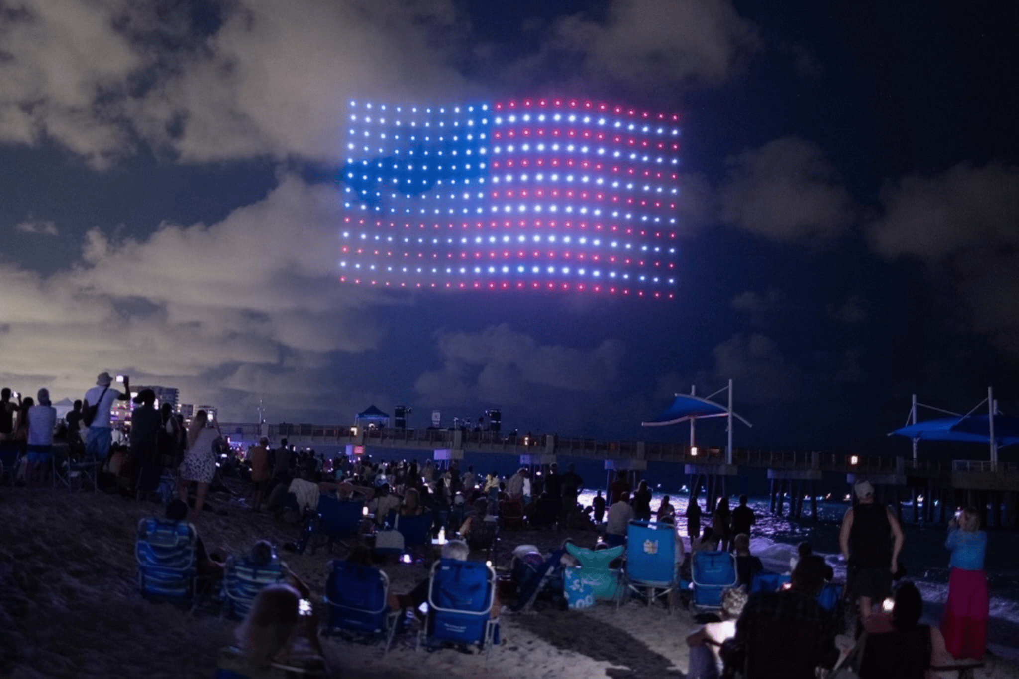 An American flag lit up in the sky at night by drones