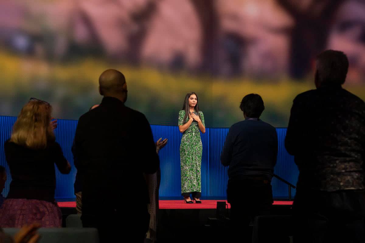 Xiye Bastida wearing a green dress, standing on stage