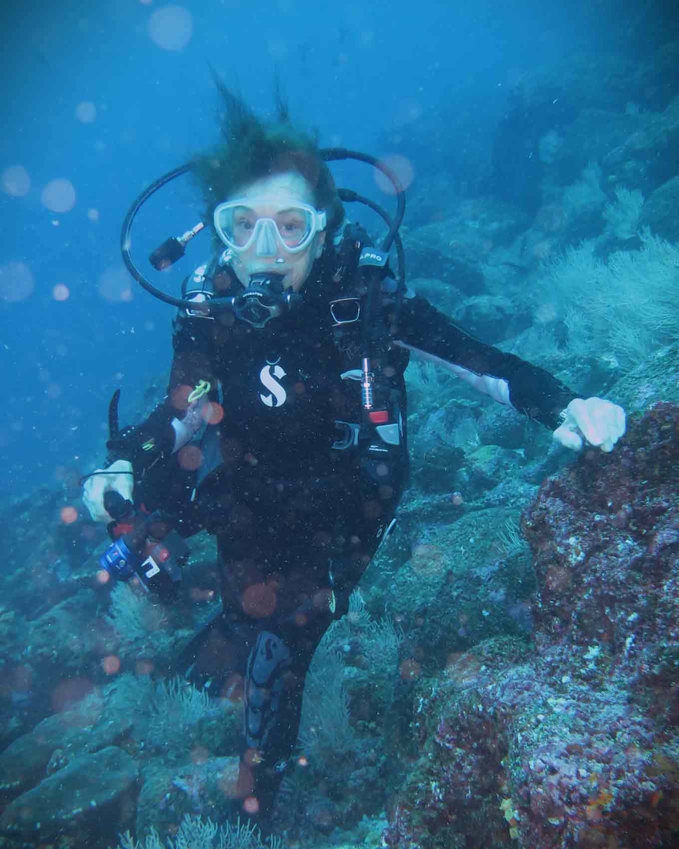 Sylvia Earle in full scuba gear next to coral underwater