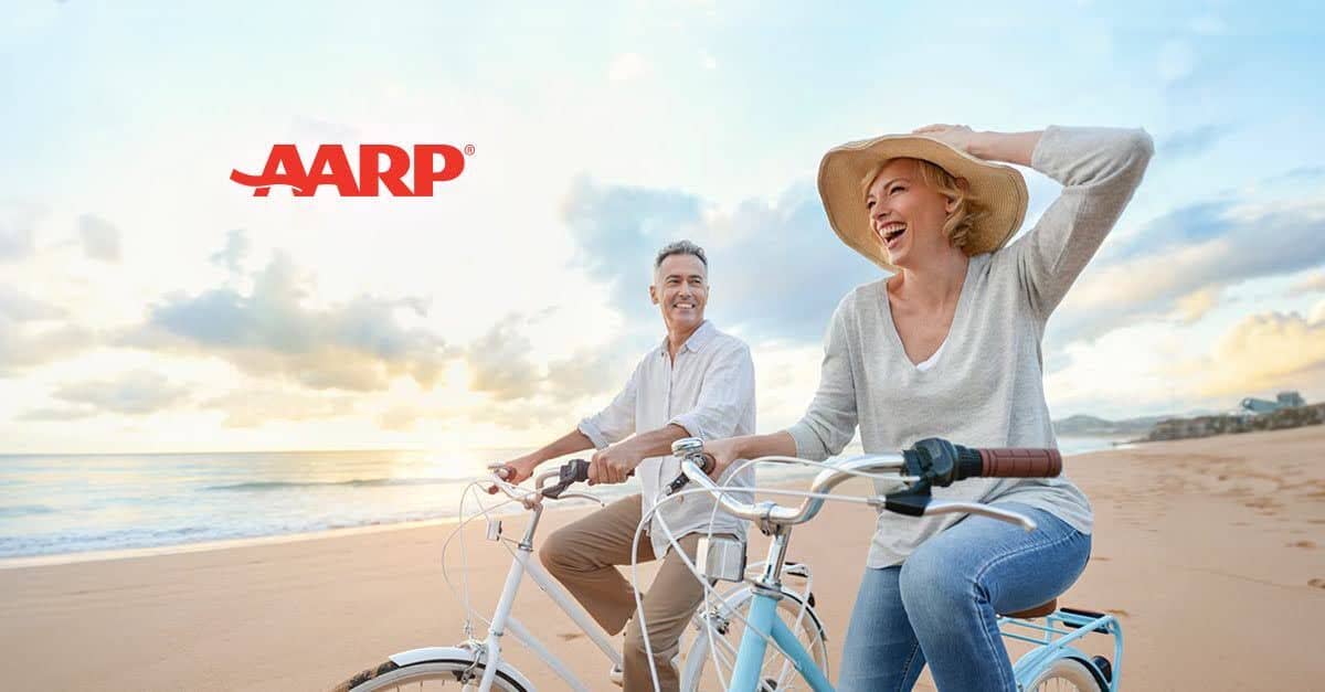 Two people smiling riding bikes on a beach