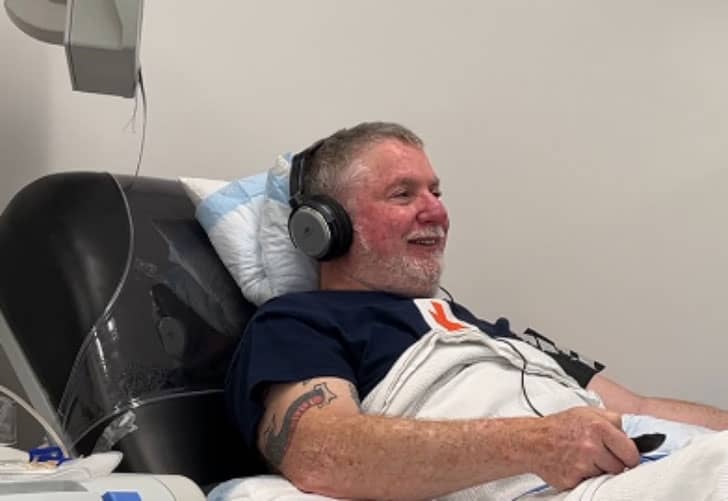 Man laying on a blood donation chair with headphones on