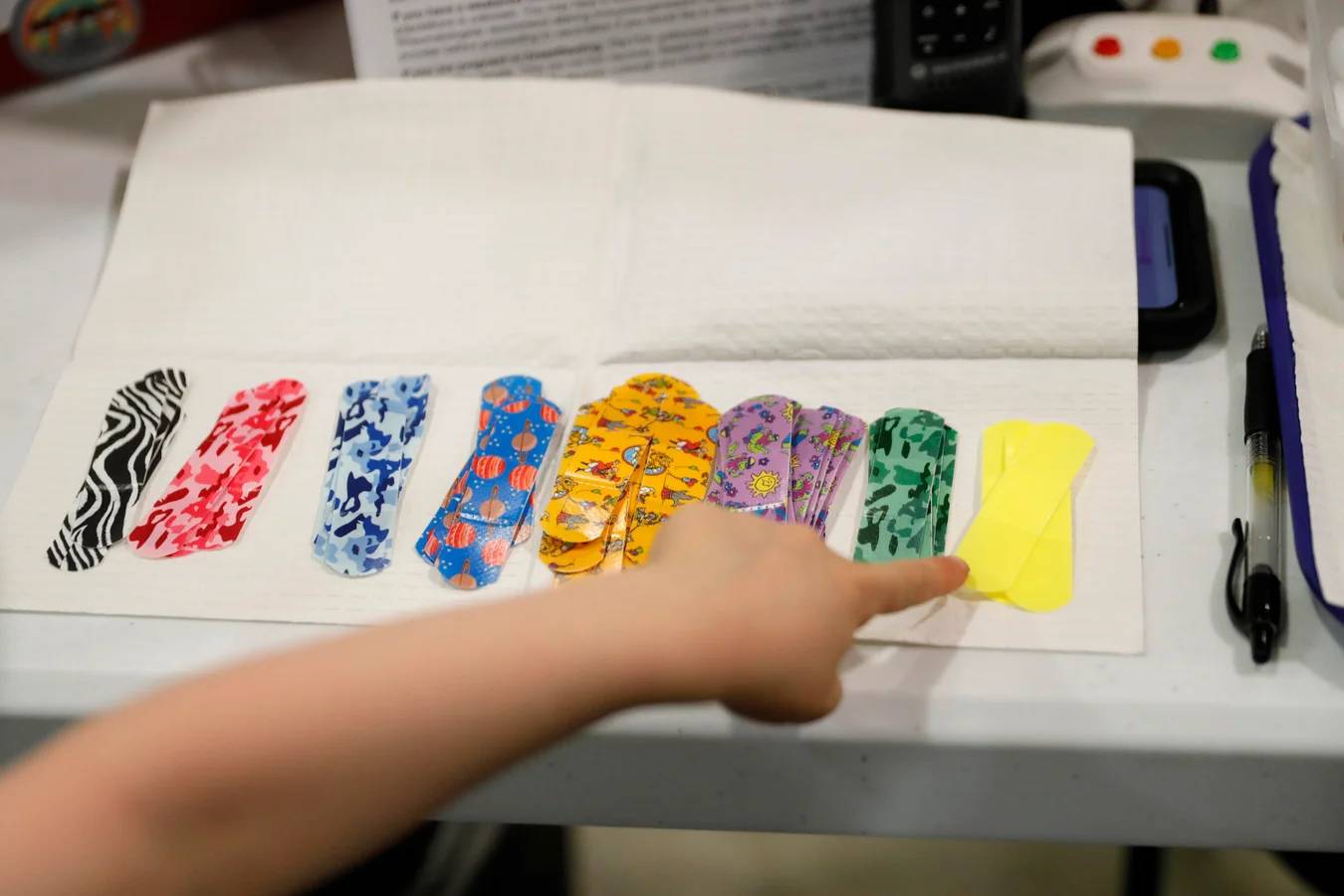 A child's hand pointing to a bright yellow bandaid option