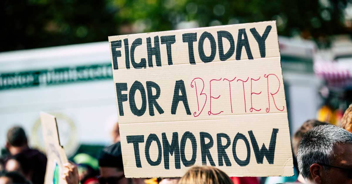 A cardboard sign with "Fight today for a better tomorrow" hand drawn on it