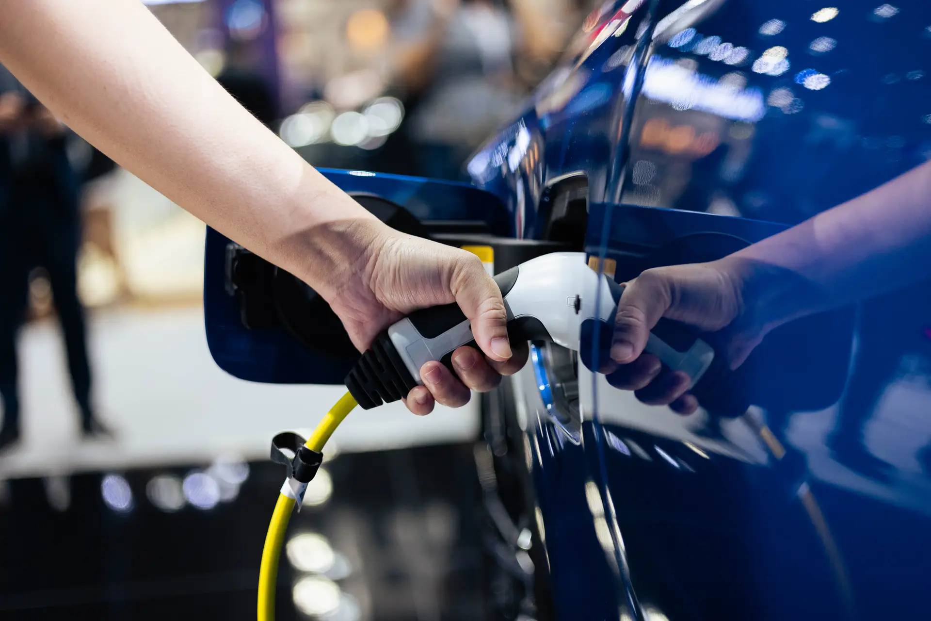 Person putting a charger in the side of a blue car