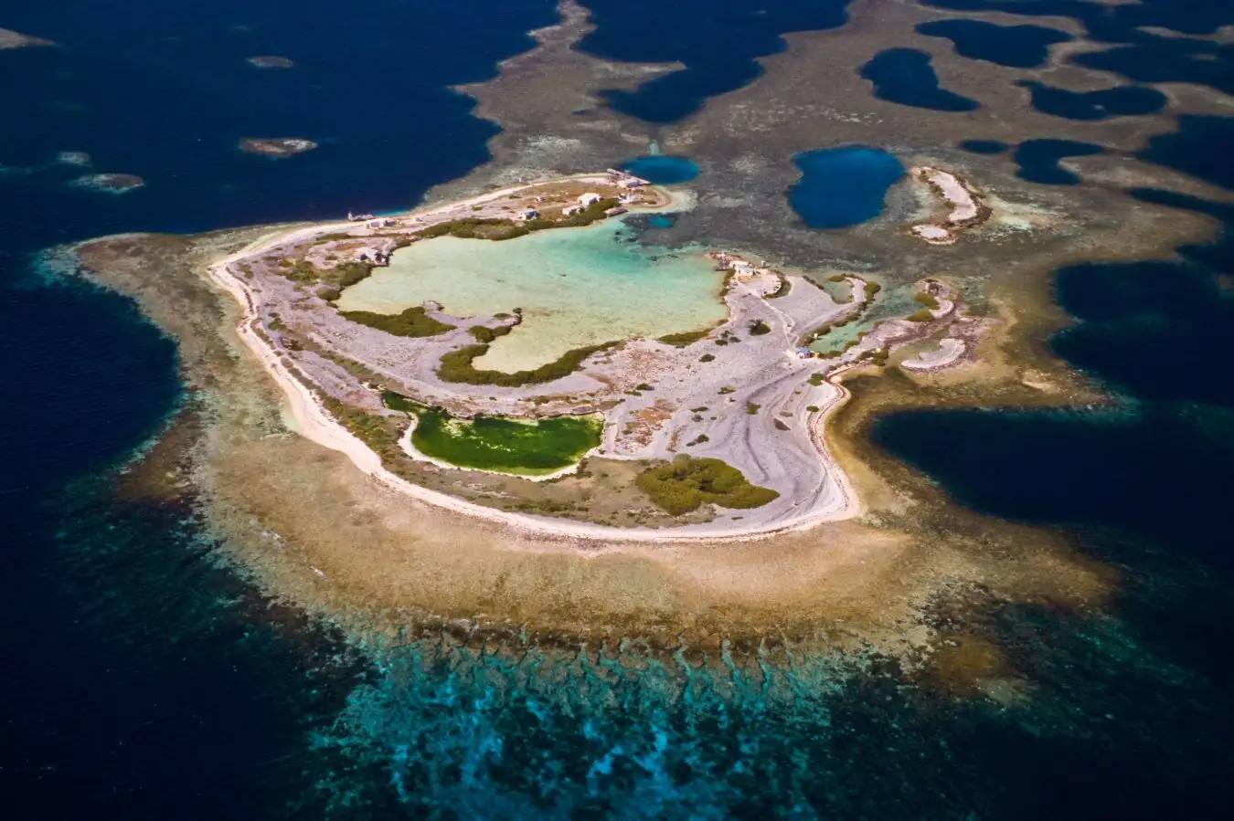 Aerial photo of a sandy island surrounded by water and reefs
