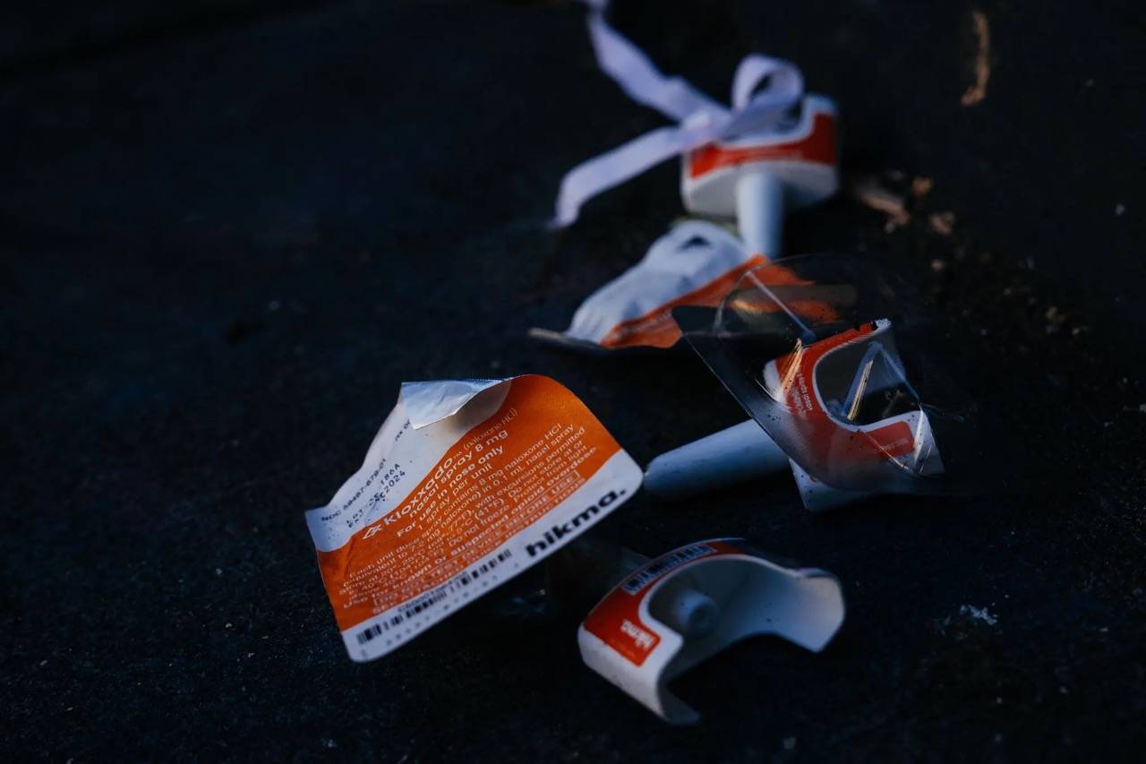 Two used naloxone nasal spray containers sitting on the ground
