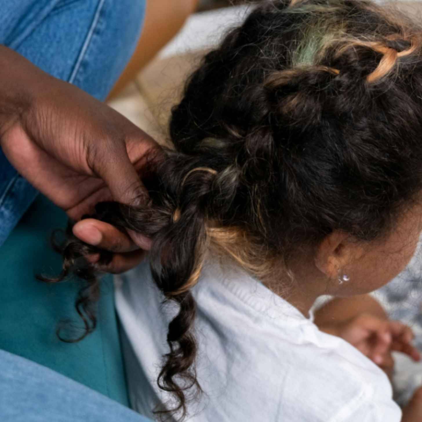 A hand french braiding dark brown-black hair