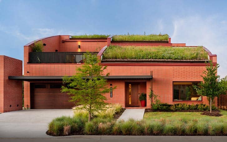 Exterior of a red brick home with green plants on the roof