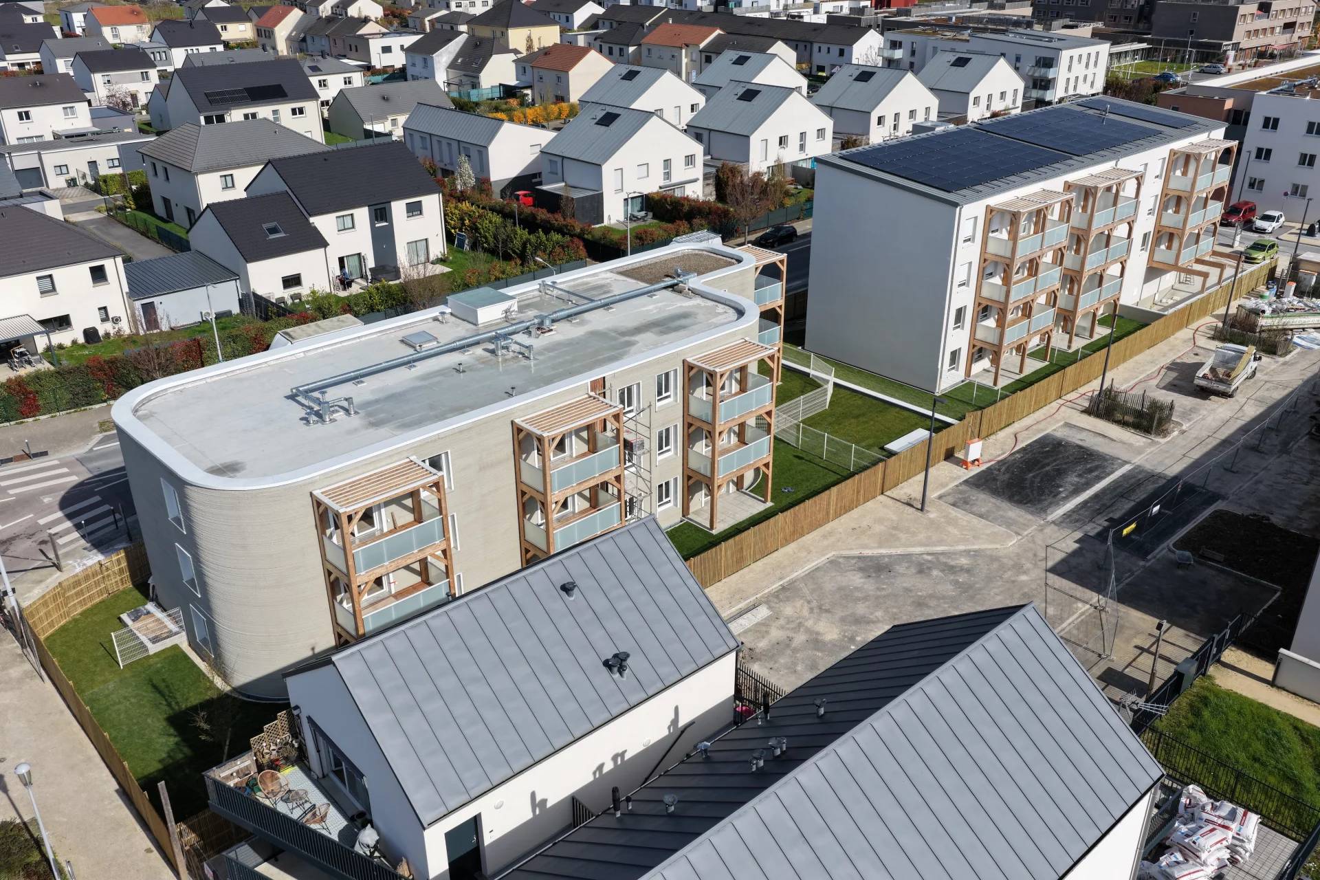 Aerial view of a 3D-printed building next toa traditional construction building