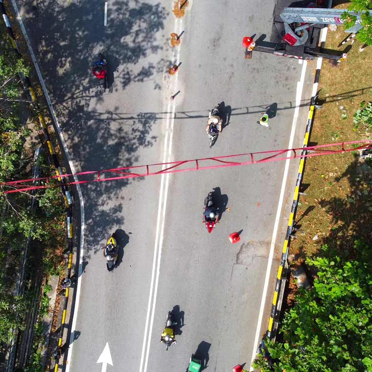 Overhead image of red firehose ladder over a road filled with scooters