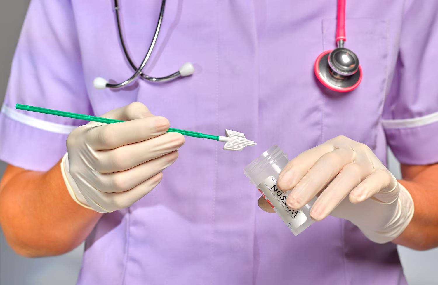 A nurse/doctor in purple scrubs holding a cervical cancer screening wand