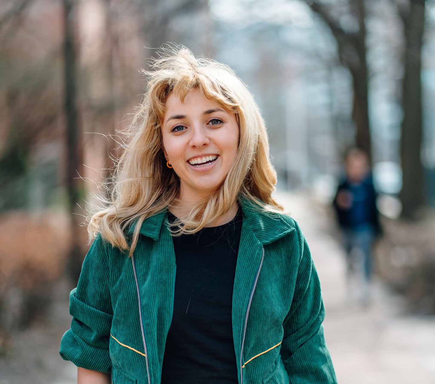 Kat Abughazaleh in a green corduroy jacket smiling at the camera