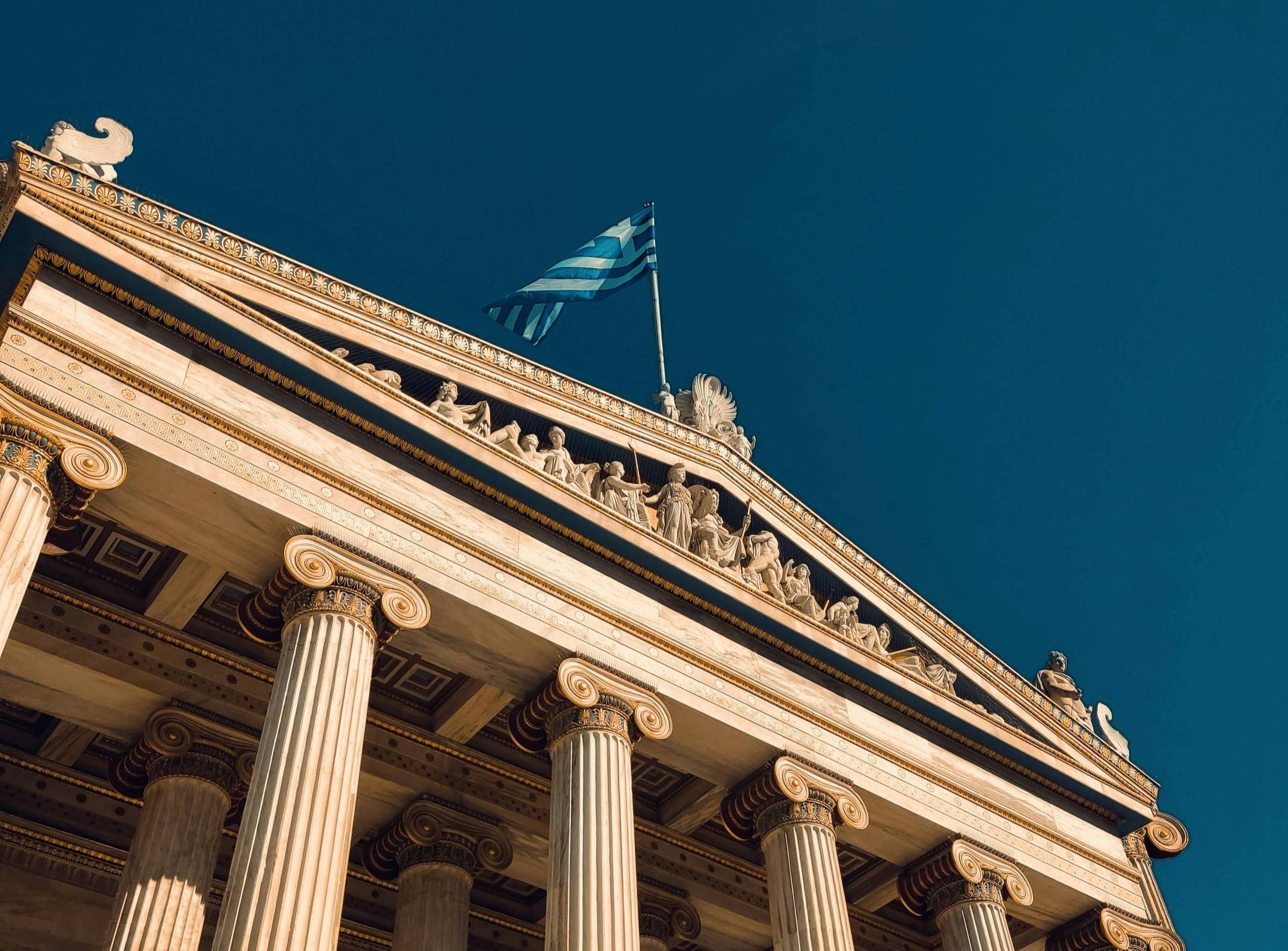 Flag of Greece on top of a building with columns on the front