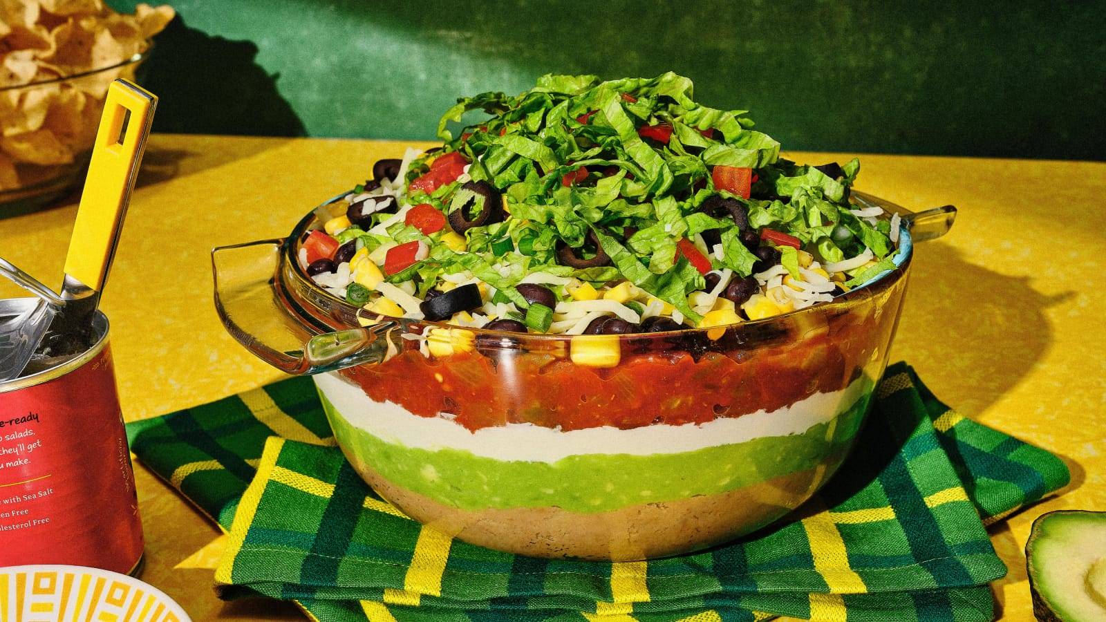 A layered bowl of dip on a yellow table