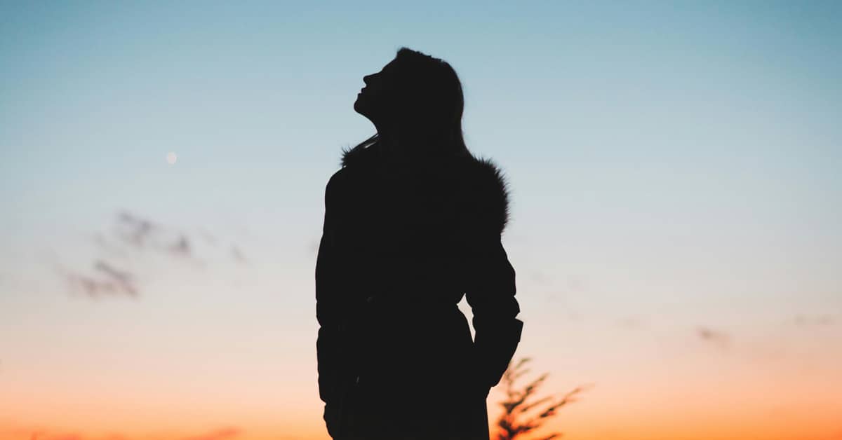 Silhouette of a person against a blue-to-orange sunrise sky