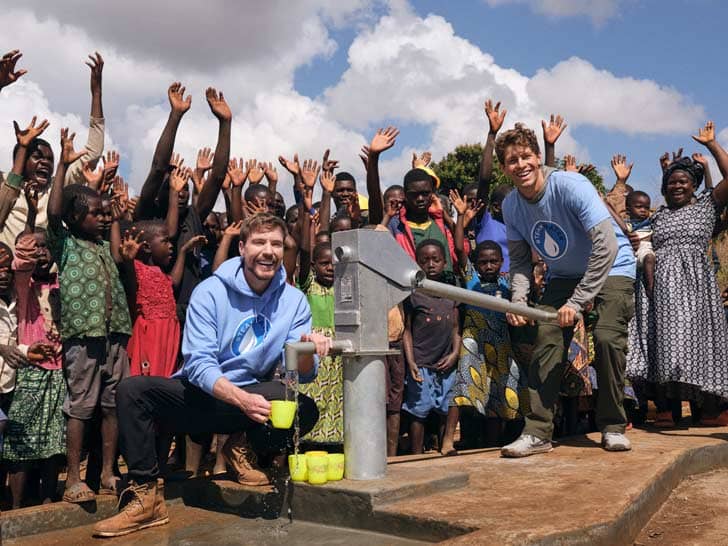 Mr Beast and Mark Rober at a well surrounded by people cheering