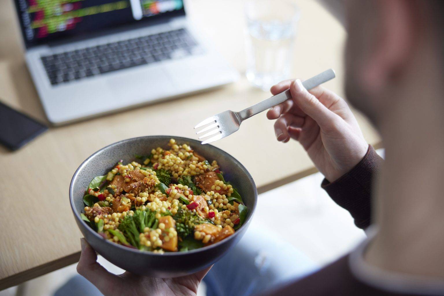 Over-the-shoulder photo of a person eating a plant-based bowl of food