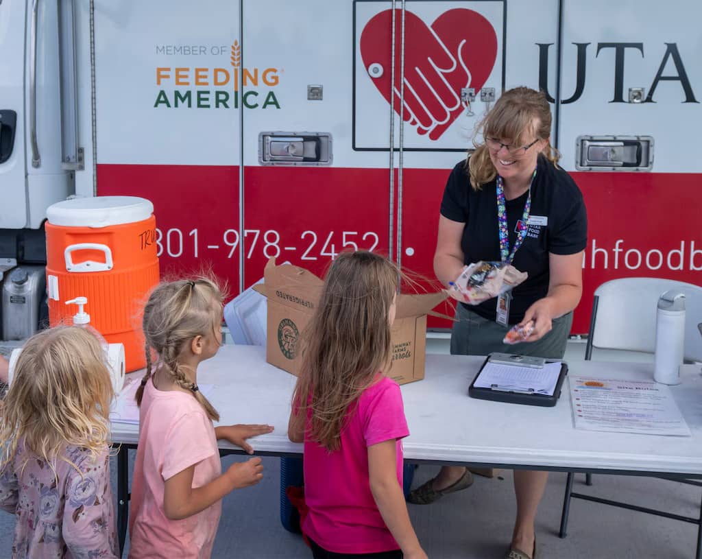 A person handing food to kids in line