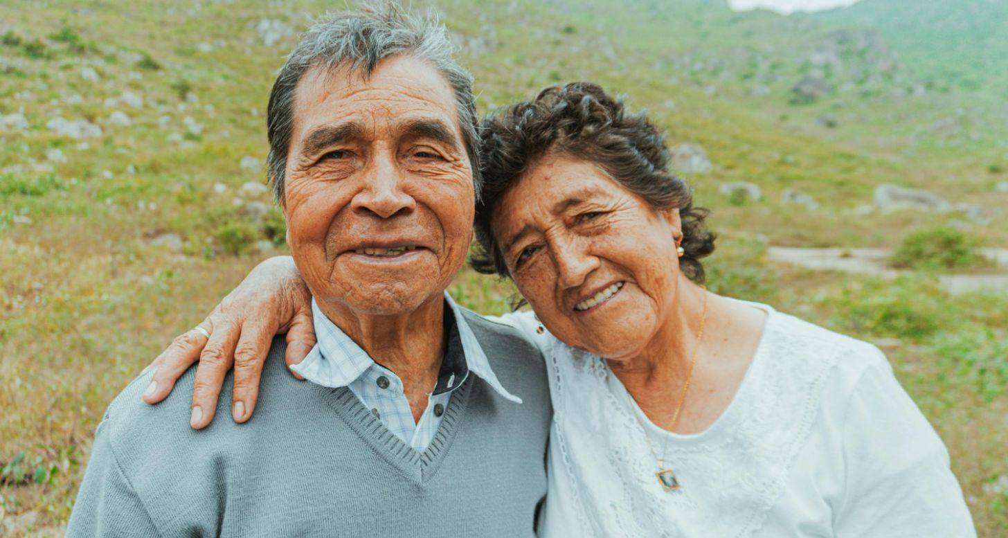 An older couple with their arms around each other, smiling