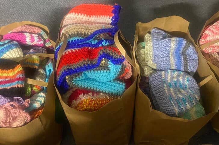 Four brown paper bags filled with knit items 