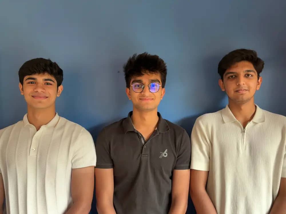 Three teens standing against a blue wall